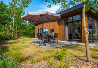 Outdoor seating area at Pavilion lodge at De Wije Werelt in the Netherlands, people sitting under a large umbrella.