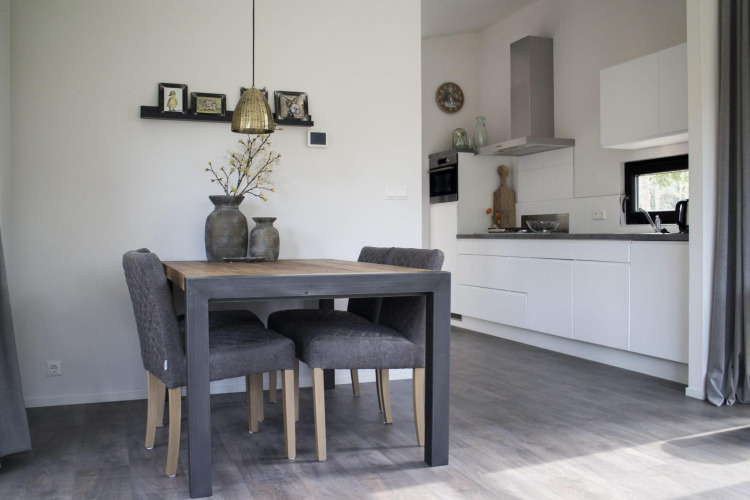 Comedor moderno y cocina en Pavilion de De Wije Werelt lodge en los Países Bajos con sillas grises y decoración.
