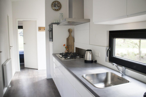 Moderne køkken område i en lodge på Pavilion at De Wije Werelt, Holland, med udsigt gennem vinduet.