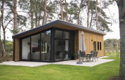 Lodge tipo pabellón moderno con grandes ventanales rodeado de árboles en De Wije Werelt, Países Bajos, exterior.