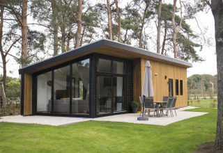 Moderne paviljoenlodge met grote glaspartijen in een bosrijke omgeving op De Wije Werelt, Nederland, buiten.