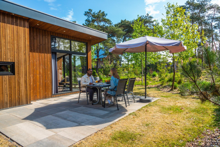 Dos personas cenando al aire libre en la cabaña Pavilion en De Wije Werelt, Países Bajos, rodeadas de naturaleza.