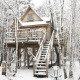 Casa del árbol nevada en Cosy Cabins, bosque de Limburg, Bélgica, refugio acogedor de invierno.
