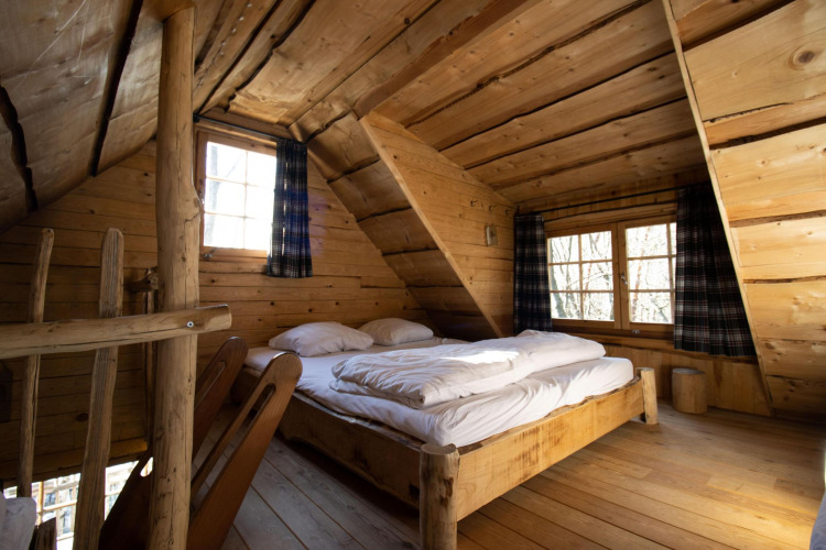 Slaapkamer in een houten boomhut bij Cosy Cabins in het bos van Limburg, België, met tweepersoonsbed.