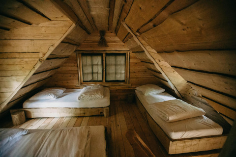 Dormitorio rústico de madera con tres camas individuales en la Tree House de Cosy Cabins, bosque de Limburgo, Bélgica.