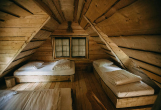 Dormitorio rústico de madera con tres camas individuales en la Tree House de Cosy Cabins, bosque de Limburgo, Bélgica.