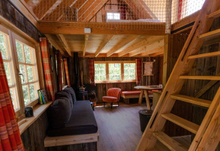 Vista interior de Tree House 1 en Cosy Cabins en el bosque de Limburgo, Bélgica, con cálida decoración de madera.