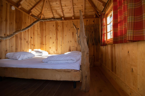 Acogedora casa del árbol con dormitorio y decoración rústica en Cosy Cabins, bosque de Limburg, Bélgica.