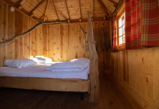 Acogedora casa del árbol con dormitorio y decoración rústica en Cosy Cabins, bosque de Limburg, Bélgica.