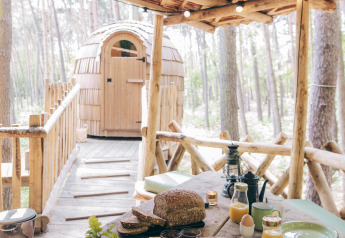 Rustic outdoor breakfast setup on a wooden deck of a tree house cabin in a forest setting in Limburg, Belgium.