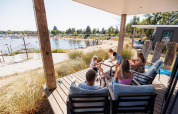 Familia disfrutando en la terraza del Beach lodge | Port en Vakantiepark Leukermeer, Países Bajos.