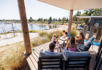 Family relaxing on the terrace of the Beach lodge | Port at Vakantiepark Leukermeer, Netherlands.