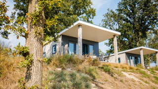 Moderne strandhytter med store terrasser omgivet af natur og træer i Vakantiepark Leukermeer, Holland.