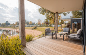 Holzterrasse mit gemütlichen Sitzmöbeln und Seeblick am Beach lodge Port im Vakantiepark Leukermeer, Niederlande.