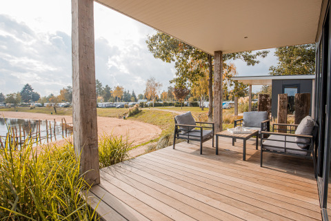 Holzterrasse mit gemütlichen Sitzmöbeln und Seeblick am Beach lodge Port im Vakantiepark Leukermeer, Niederlande.