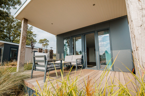 Moderne strandlodge med terrasse og udendørs siddepladser ved Vakantiepark Leukermeer i Holland.