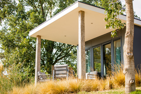 Moderne lodge met terras en buitenzitjes bij Vakantiepark Leukermeer, Nederland, omringd door natuur.