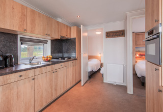 Cocina moderna y dos dormitorios en una cabaña de playa en Vakantiepark Leukermeer, Países Bajos.
