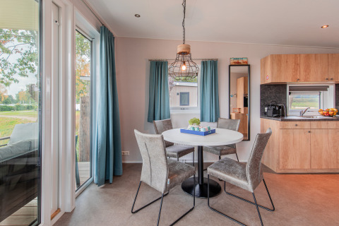 Moderne spiseplads med firkantet bord, fire stole og udsigt til natur, i Beach lodge ved Vakantiepark Leukermeer.