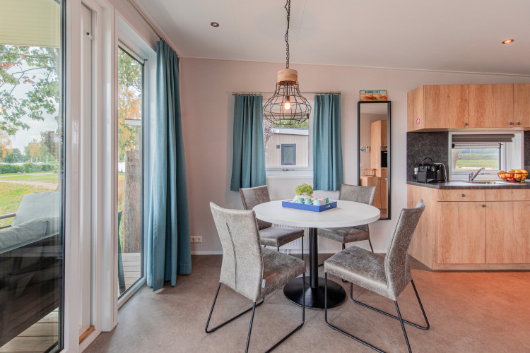 Comedor luminoso con mesa redonda y cuatro sillas en Beach lodge Port de Vakantiepark Leukermeer, Países Bajos.