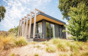 Pequeña casa moderna Beach lodge en Vakantiepark Leukermeer, Países Bajos, rodeada de vegetación y dunas.