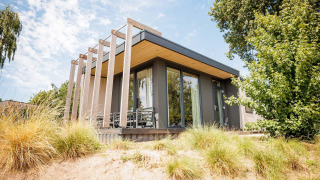 Moderne tiny house Beach lodge op Vakantiepark Leukermeer, Nederland, met grote ramen en veel natuur.