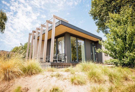 Modern Beach Lodge tiny house at Vakantiepark Leukermeer, Netherlands, with large windows and natural landscape.