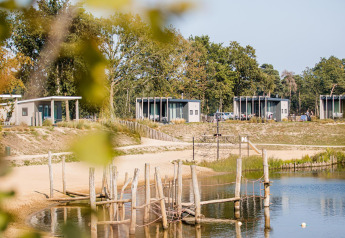 Moderni lodge sulla spiaggia che si affacciano sul lago con spiaggia sabbiosa nel Vakantiepark Leukermeer, Paesi Bassi.