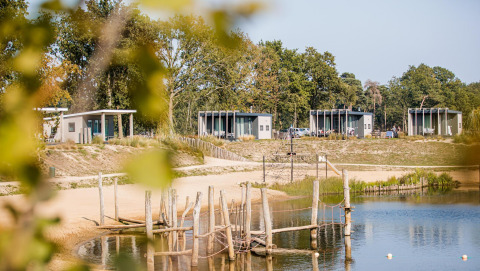Udsigt over moderne strandhytter ved søen med sandstrand og legeplads i Vakantiepark Leukermeer, Holland.
