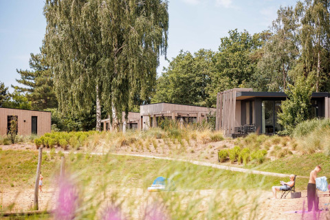 Tiny houses aan het strand in Vakantiepark Leukermeer, Nederland, omgeven door bomen en zand.