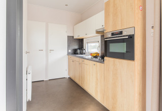 Modern small kitchen with wood cabinets at Beach Lodge, Vakantiepark Leukermeer, Netherlands.