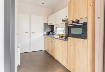 Moderne, kompakt køkken i Beach Lodge, Vakantiepark Leukermeer, Holland, med lyse træelementer.