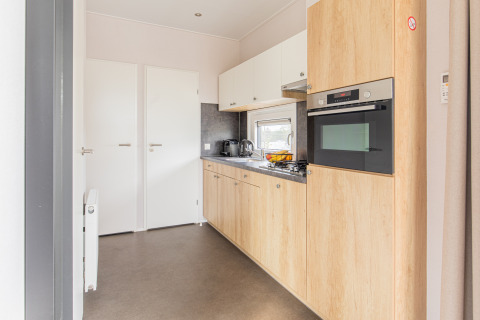 Cocina moderna y pequeña con gabinetes de madera en Beach Lodge, Vakantiepark Leukermeer, Países Bajos.