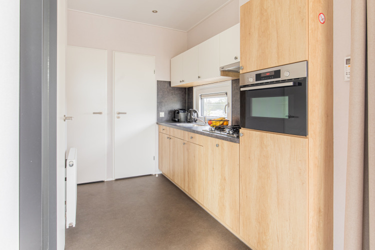 Cocina moderna y pequeña con gabinetes de madera en Beach Lodge, Vakantiepark Leukermeer, Países Bajos.
