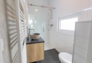 Moderne, kompakt badeværelse i Beach lodge på Vakantiepark Leukermeer, Holland, med bruser og stenvask.