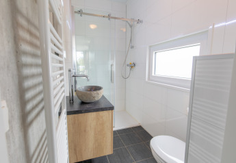 Moderne, kompakt badeværelse i Beach lodge på Vakantiepark Leukermeer, Holland, med bruser og stenvask.