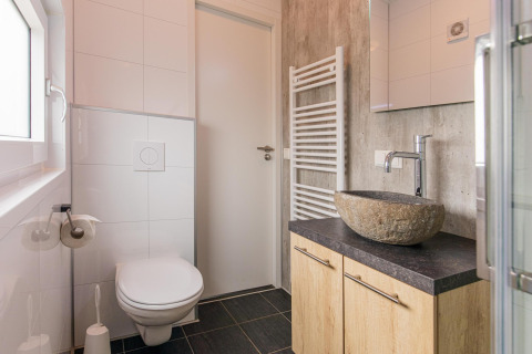 Modern tiny bathroom at Beach Lodge, Vakantiepark Leukermeer, with stone sink and wall-mounted toilet.