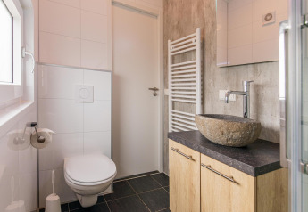 Moderne, lille badeværelse i Beach Lodge på Vakantiepark Leukermeer med stenvask og væghængt toilet.