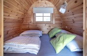 Piccola casa in legno a Water bubbles, Marina Parcs Almere, letti con cuscini verdi in evidenza.