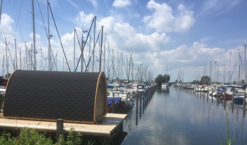 La tiny house Water Bubbles en Marina Parcs Almere, Países Bajos, rodeada de barcos en un puerto deportivo.