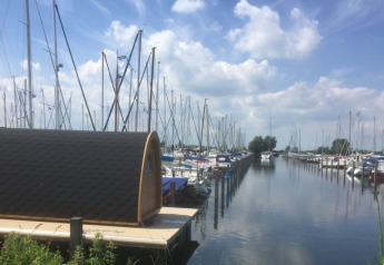 La tiny house Water Bubbles en Marina Parcs Almere, Países Bajos, rodeada de barcos en un puerto deportivo.
