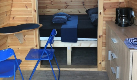 Interior of Water bubbles tiny house at Marina Parcs Almere, Netherlands, featuring blue chairs and a bed.