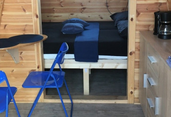 Interno della tiny house Water bubbles a Marina Parcs Almere, Paesi Bassi, con sedie blu e letto.