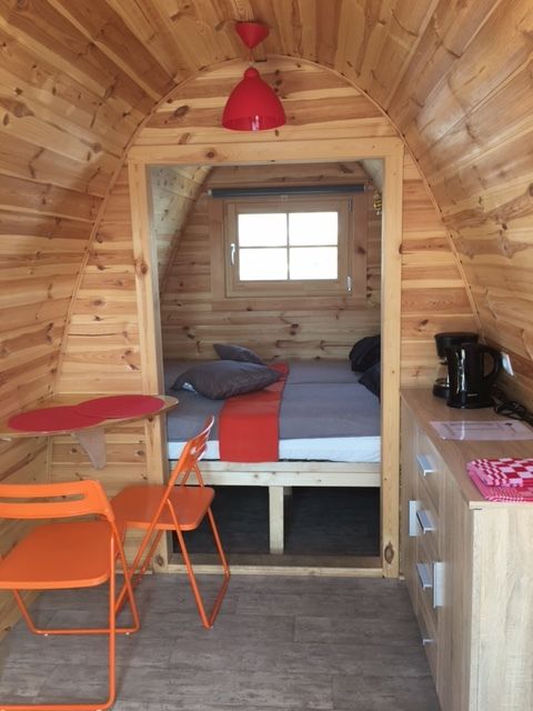 Interior de una tiny house llamada Water bubbles en Marina Parcs Almere, Países Bajos, con sillas naranjas.
