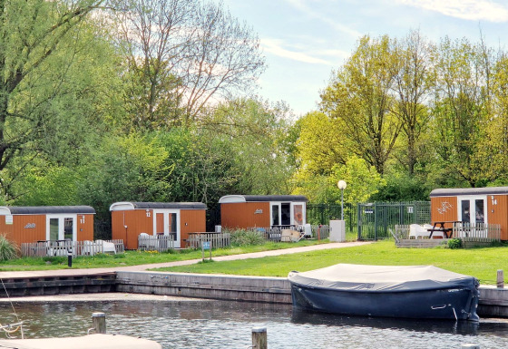 Tiny Wagons bei Marina Parcs Naarden in den Niederlanden mit Wasser und grüner Umgebung.