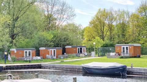 Tiny wagons en Marina Parcs Naarden, Países Bajos, rodeados de naturaleza y una pequeña marina al frente.