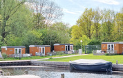 Tiny wagons en Marina Parcs Naarden, Países Bajos, rodeados de naturaleza y una pequeña marina al frente.