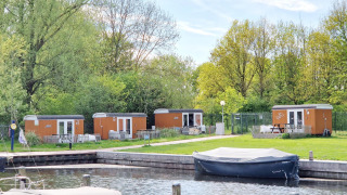 Tiny wagons en Marina Parcs Naarden, Países Bajos, rodeados de naturaleza y una pequeña marina al frente.