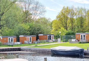 Tiny wagons ved Marina Parcs Naarden, Holland, omgivet af grønne træer og en lille havn foran.