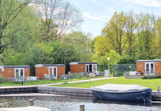 Tiny wagons en Marina Parcs Naarden, Países Bajos, rodeados de naturaleza y una pequeña marina al frente.